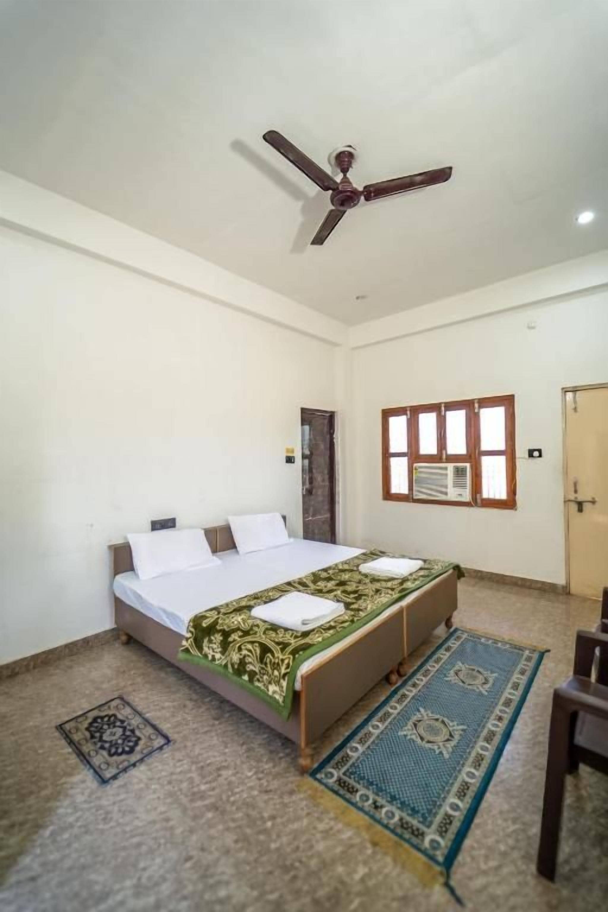 Een slaapkamer met een bed, een plafondventilator, een raam en een deur.