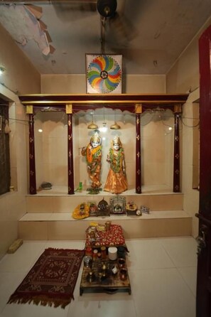 A shrine with statues, a colorful ceiling fan, and a carpeted floor.