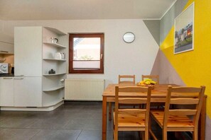 Une cuisine de taille réduite comprenant un coin repas, un radiateur, une horloge et une fenêtre avec des stores.