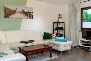 Ein Wohnzimmer mit einer Couch, einem Couchtisch und einem Fernseher.