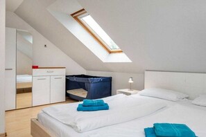 A bedroom with a skylight, a bunk bed, a bedside table with a lamp, and a bed with neatly folded towels. - Holiday home with 1 bedroom (Zingst (Ostseeheilbad))