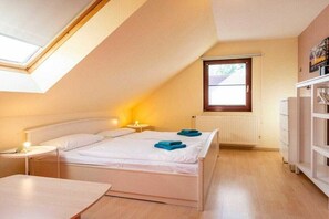 Ein Schlafzimmer mit Dachfenster, einem Bett mit weißer Bettwäsche, einem Nachttisch mit Lampe und einem Heizkörper.