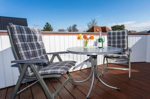 An outdoor seating area with two chairs and a table, a bottle of water, and a vase with flowers. - Holiday apartment with 1 bedroom (Zingst)