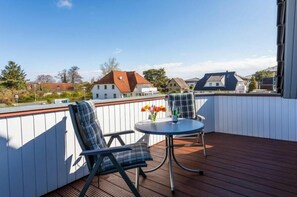 A deck with two chairs and a table, overlooking a residential area. - Holiday apartment with 1 bedroom (Zingst)