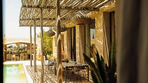 Een terras buiten met een zwembad, een houten pergola en tuinmeubilair.