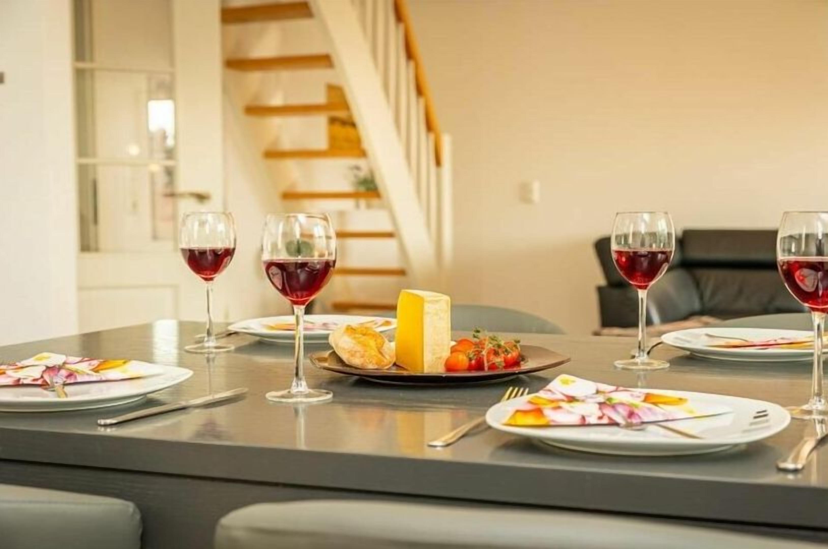 Une table à manger dressée avec des assiettes, des verres et un plateau de fromages.