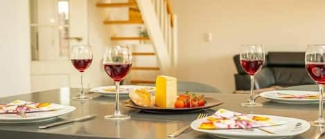 Une table à manger dressée avec des assiettes, des verres et un plateau de fromages.