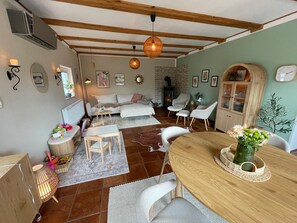 Un salon chaleureux avec une cheminée, une table à manger avec des chaises et un mur en pierre.