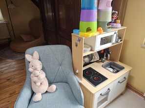 Une cuisine miniature avec un fourneau, un évier et des tiroirs de rangement, ainsi qu’un jouet en peluche et une figurine placés sur le dessus.