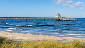 A beach with a pier extending into the water, featuring a dome structure. - Residence Am Strand 1-16 (Seeheilbad Zingst)