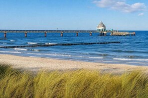 Ein Strand mit einem Steg, der ins Wasser führt, mit einer Kuppelstruktur.