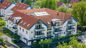 A multi-story residential building with a red-tiled roof, balconies, and a garden area. - Residence Am Strand 1-16 (Seeheilbad Zingst)