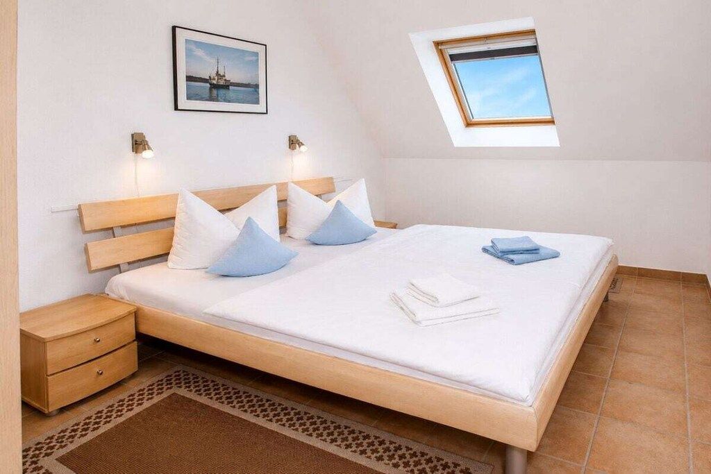 A bedroom with a bed, nightstands, a window, and a picture on the wall.