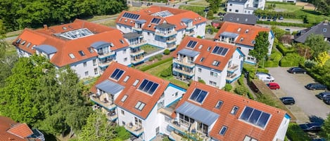 A residential area with multiple two-story houses featuring red-tiled roofs and solar panels.