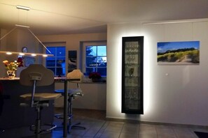 Eine moderne Küche mit Bar, einem hohen Glaskasten und einem Fenster mit Blick ins Freie.