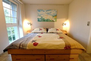 Ein Bett mit floralem Überwurf, zwei Nachttischlampen und ein Bild an der Wand.