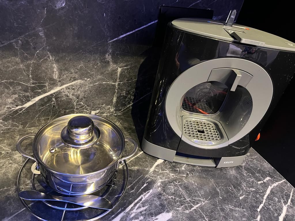 A kitchen with a coffee maker and a pot on a marble countertop.