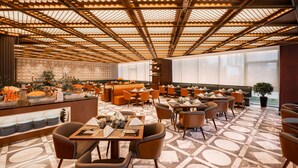 Een restaurant met een gedessineerd plafond, een buffetgedeelte en een zithoek met tafels en stoelen.
