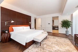 Un dormitorio de hotel moderno con una cama grande, lámparas de noche, un teléfono en la mesita y una planta en maceta.