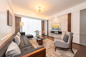 Una sala de estar moderna con un sofá, un sillón, una mesa de centro y un televisor montado en la pared.