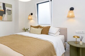 A neatly arranged bedroom with a bed, pillows, a bedside table, and wall-mounted lamps. - Victoria - Holiday Apartment in Malaga (Málaga)