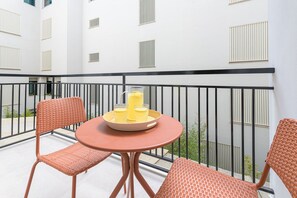 A balcony with two wicker chairs, a small round table, and a tray with two glasses of orange juice. - Victoria - Holiday Apartment in Malaga (Málaga)