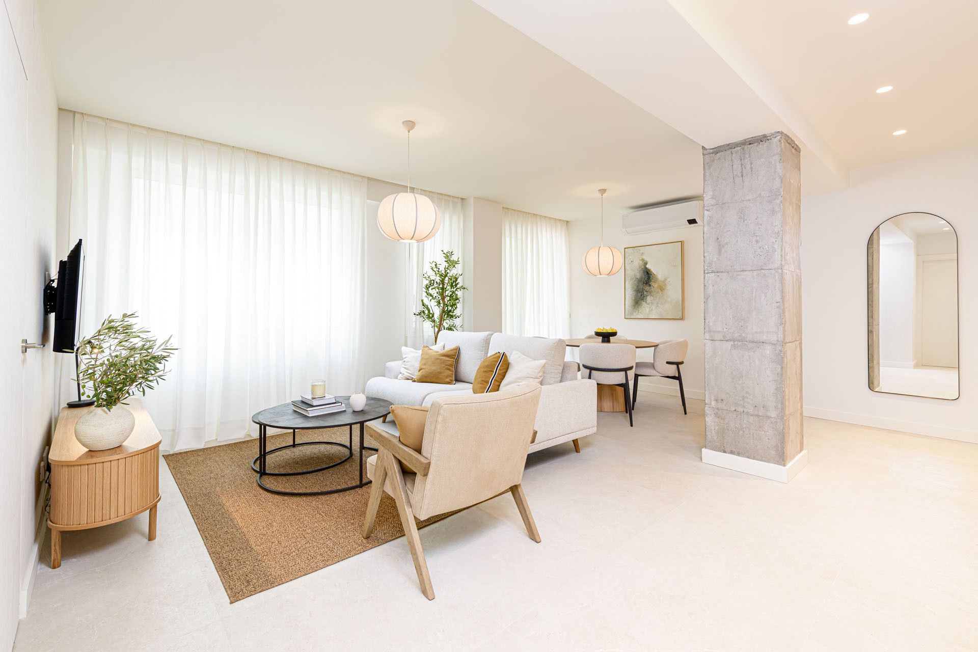A modern living room with a sofa, coffee table, and a dining area.