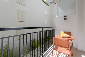 A balcony with a black railing, a wicker chair, a small table, and a potted plant. - Victoria - Holiday Apartment in Malaga (Málaga)