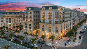 Un hôtel à plusieurs étages, doté d’une entrée imposante, de nombreux balcons et d’une façade bien éclairée.