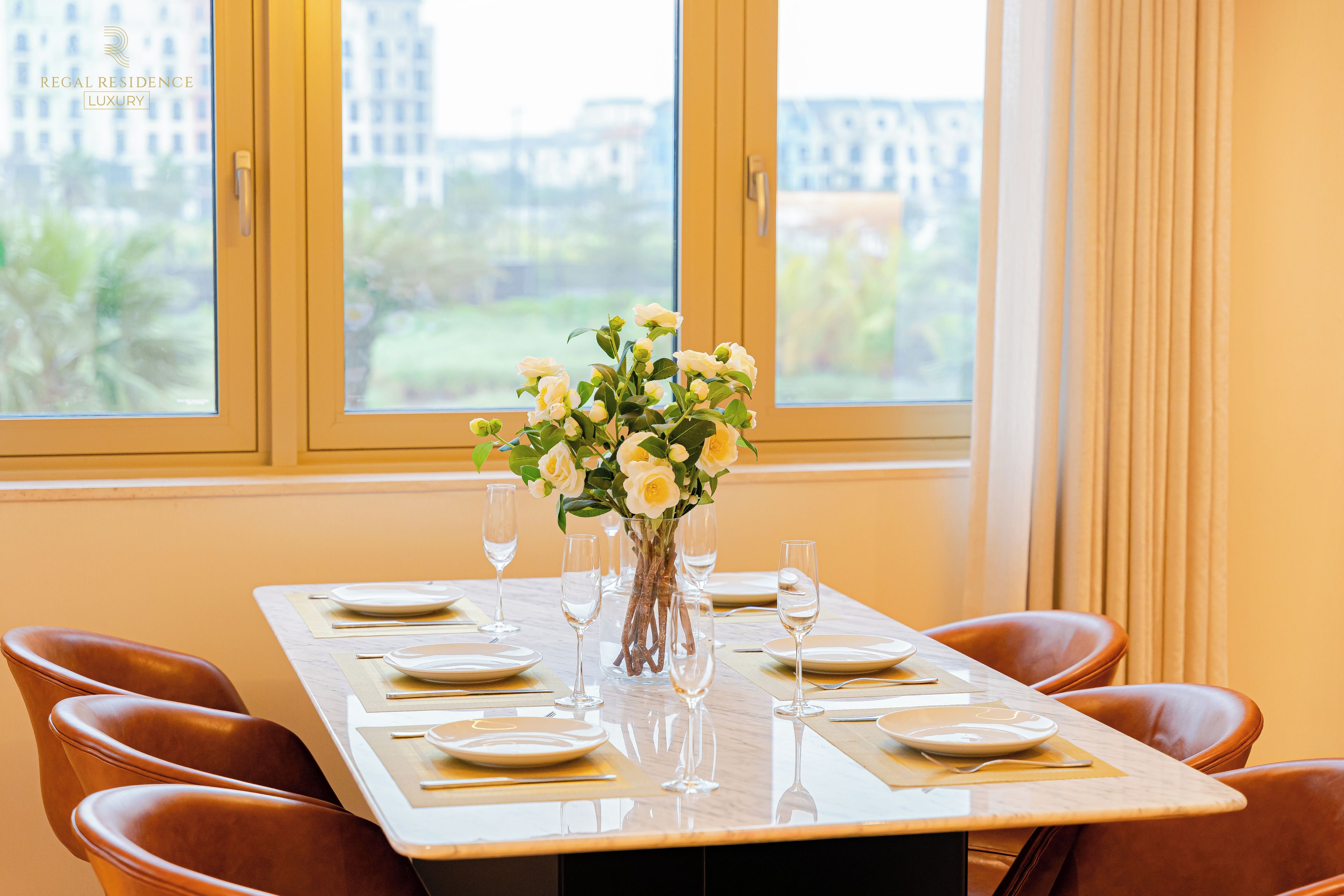 A dining table set for six with a vase of flowers, six wine glasses, and plates.