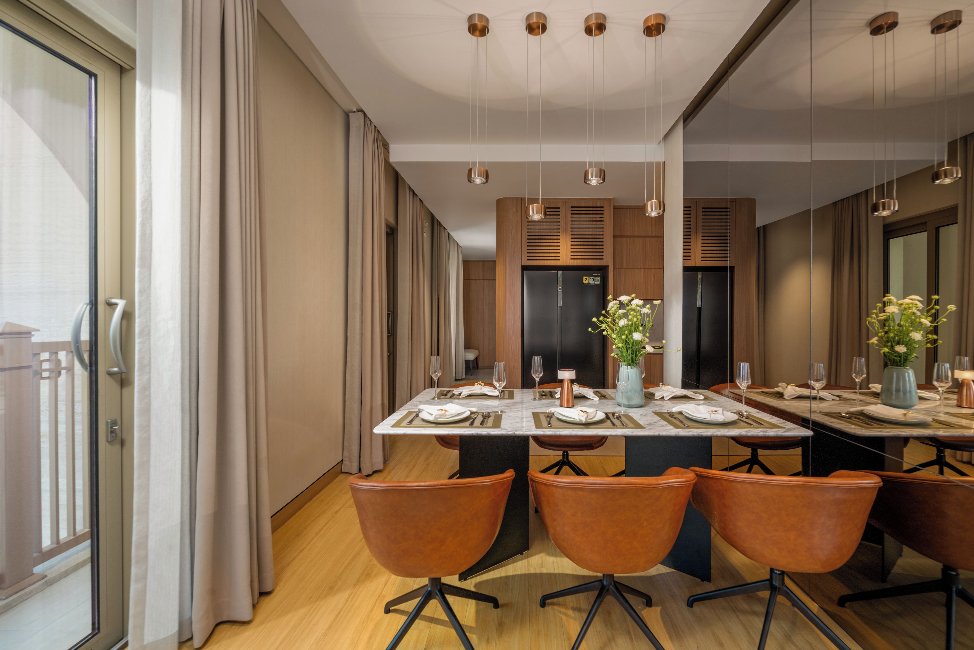 A modern dining area with a marble table, wooden chairs, and a central vase with flowers.