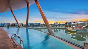 Ein Innenpool mit freiem Blick auf die umliegenden Gebäude und einen Sonnenuntergangshimmel.