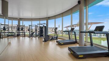 Ein Fitnessstudio mit unterschiedlichen Trainingsgeräten, großen Fenstern und Blick auf Gebäude.