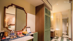 Une salle de bain d’hôtel avec un miroir, des meubles verts, un lavabo et un espace douche.