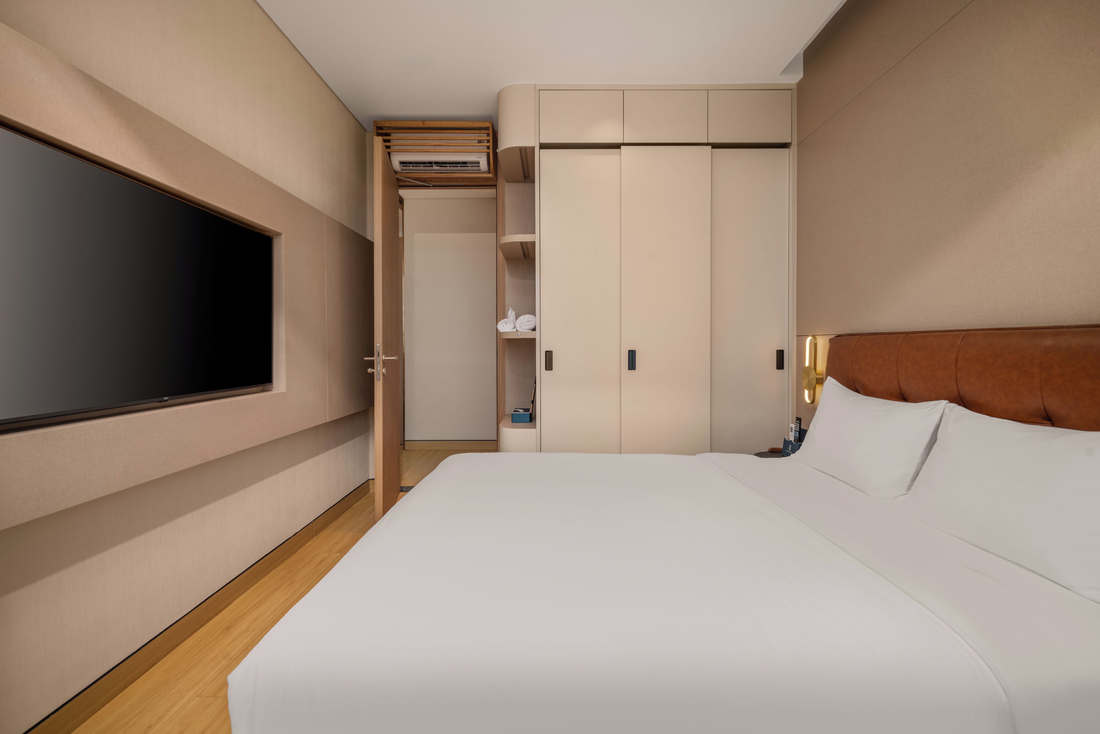 A hotel room with a bed, a television, a wardrobe, and a bathroom.