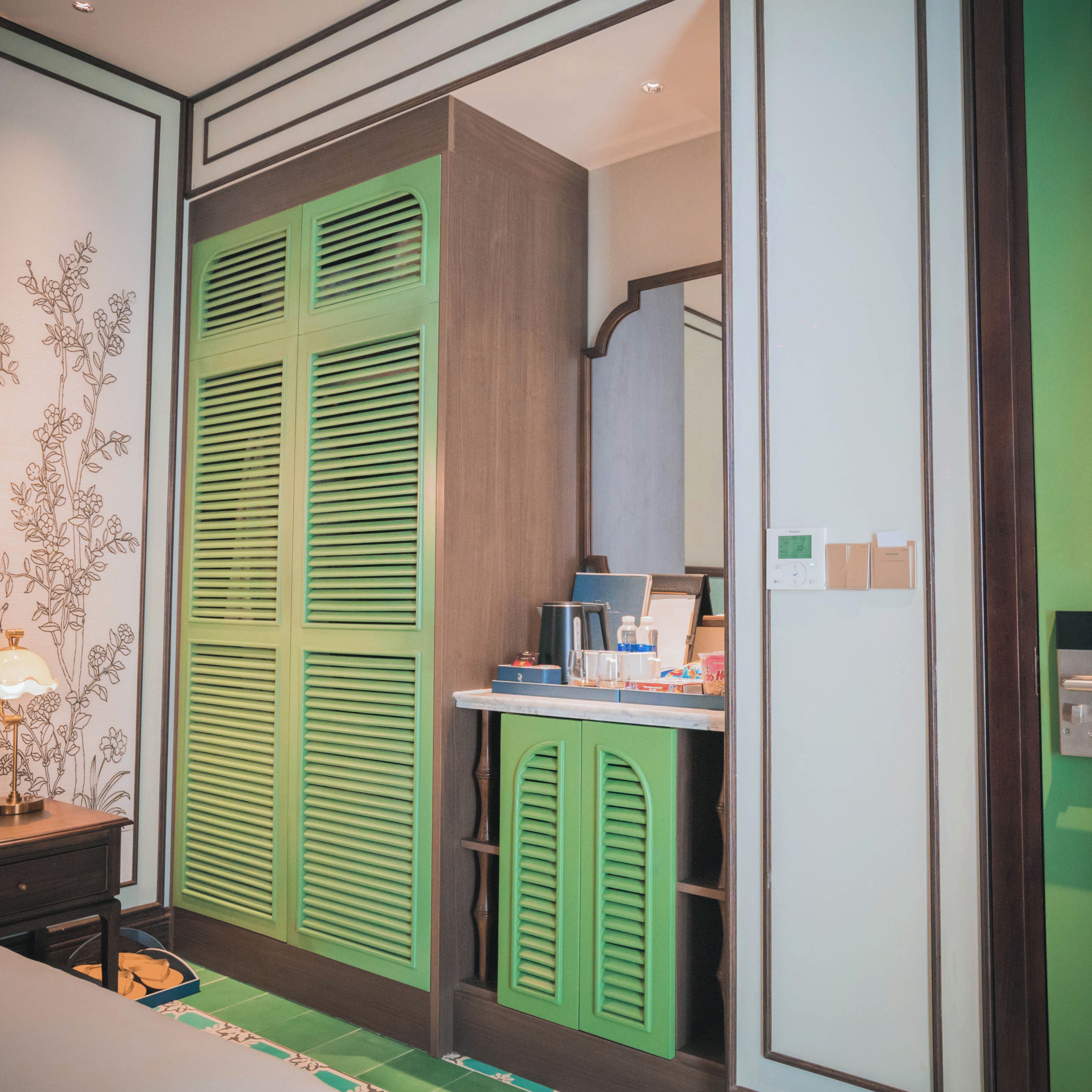 A room with a green wardrobe, a mirror, and a desk with various items.