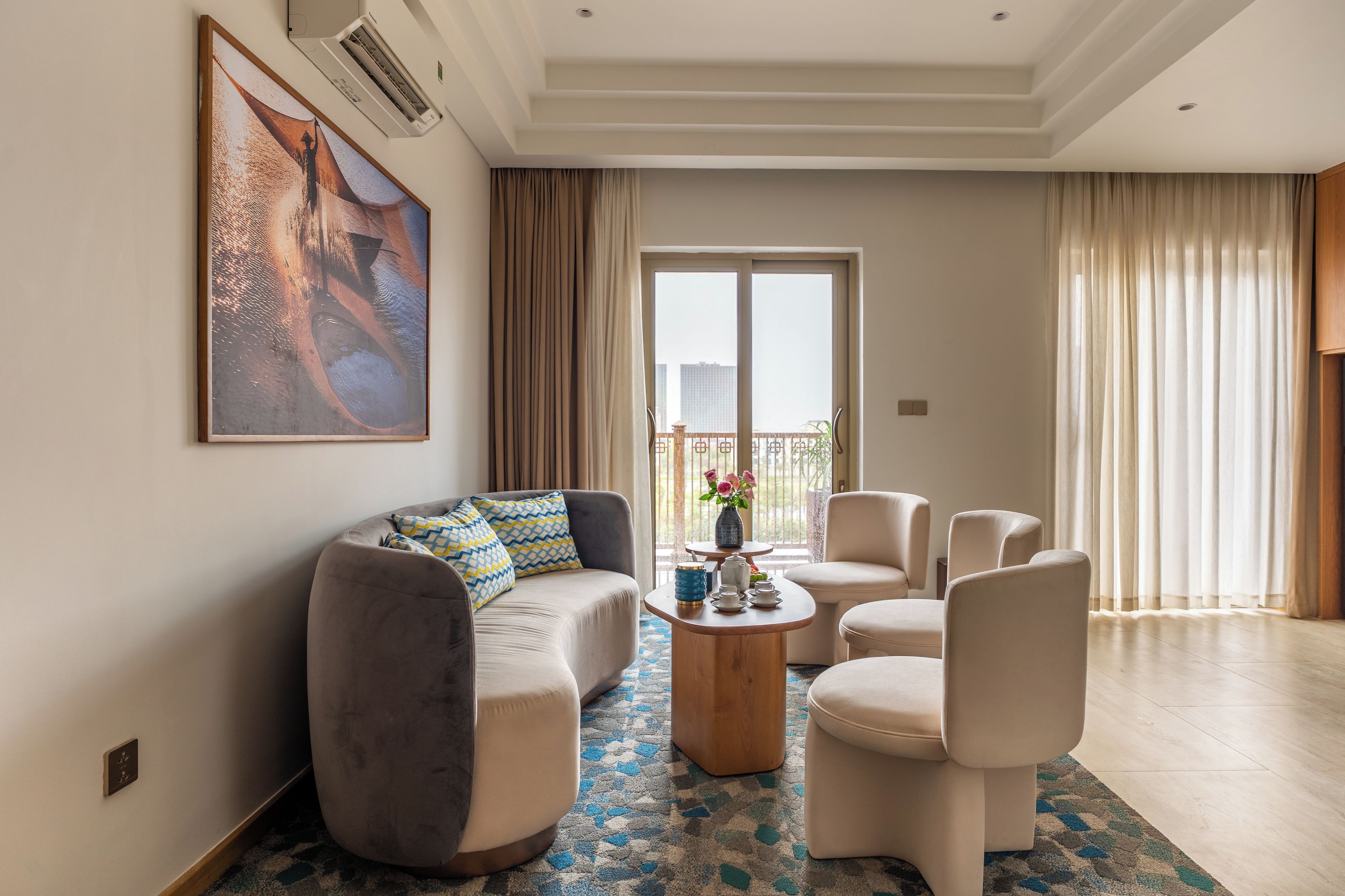 A modern living room with a sofa, chairs, a coffee table, and a large painting on the wall.