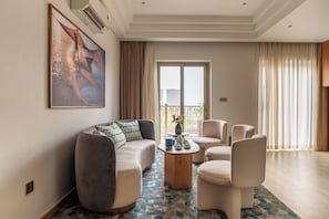 A modern living room with a sofa, chairs, a coffee table, and a large painting on the wall.