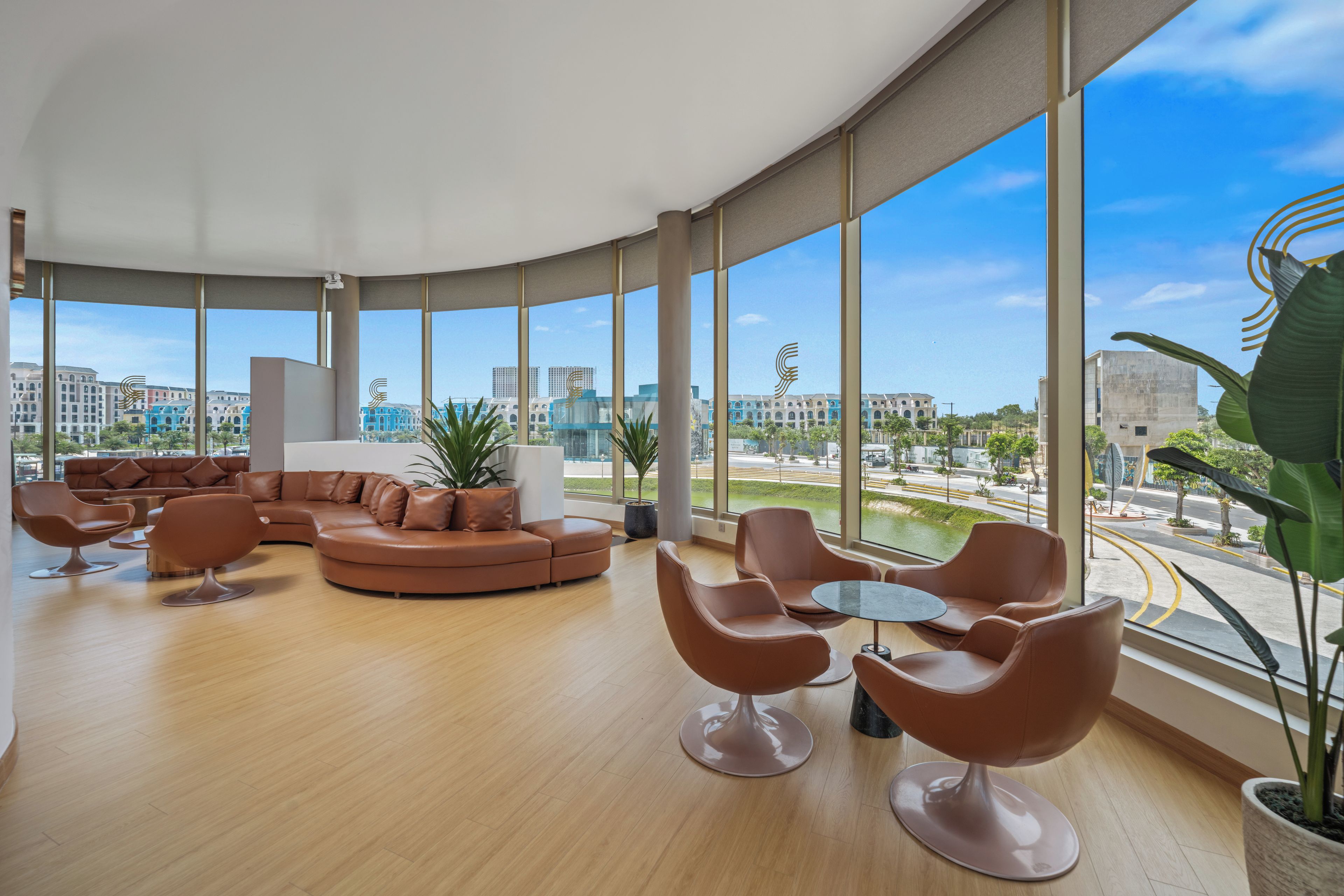A spacious lounge area with a curved ceiling, large windows offering a city view, and modern furniture.