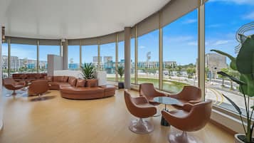 A spacious lounge area with a curved ceiling, large windows offering a city view, and modern furniture.