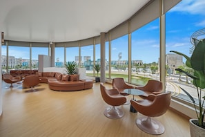 A spacious lounge area with a curved ceiling, large windows offering a city view, and modern furniture.