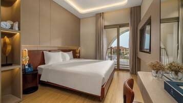 A hotel room with a bed, bedside table, lamp, and a view of the outside.