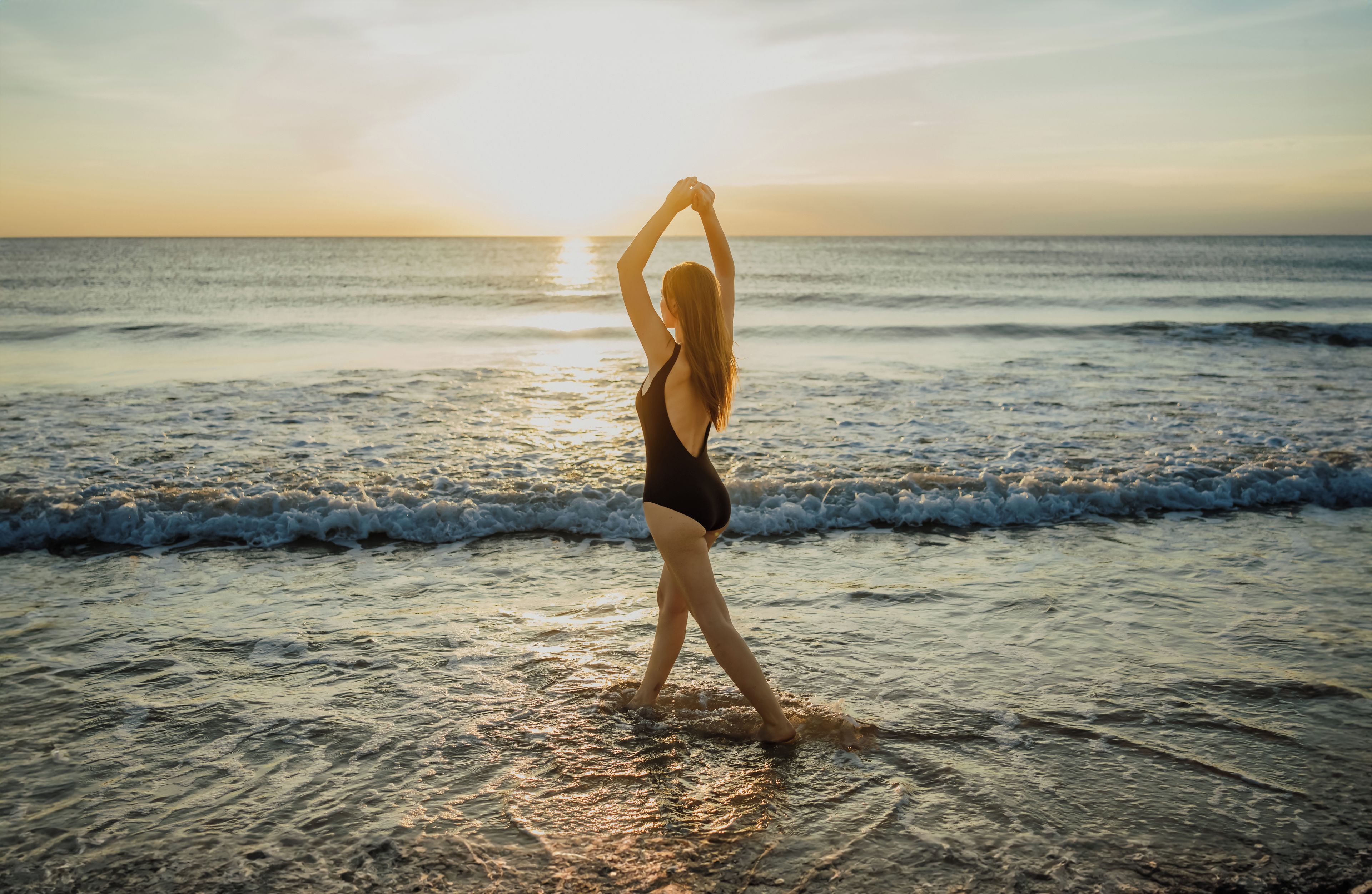 A person standing on a beach with the ocean in the background.