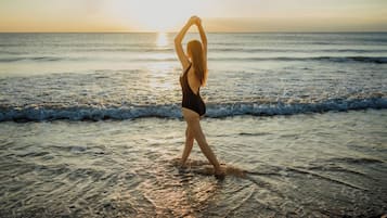 A person standing on a beach with the ocean in the background.