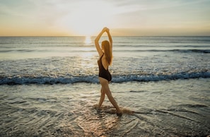 A person standing on a beach with the ocean in the background.