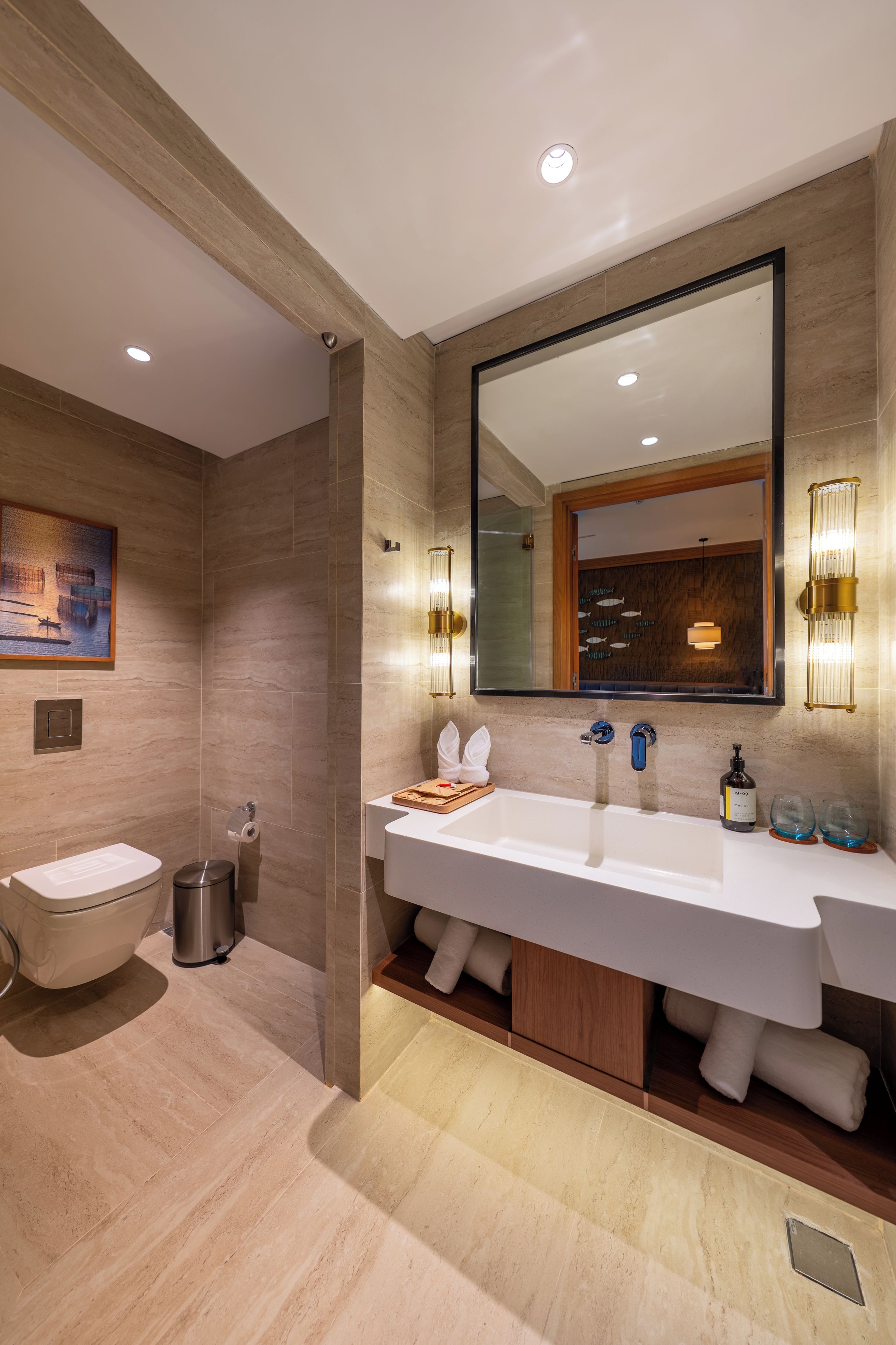 A modern bathroom with a large mirror, dual sinks, and a toilet.