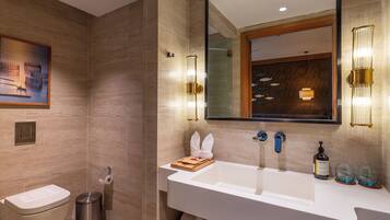A modern bathroom with a large mirror, dual sinks, and a toilet.