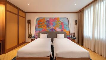 A hotel room with two beds, a large colorful map on the wall, wooden furniture, and a window with curtains.