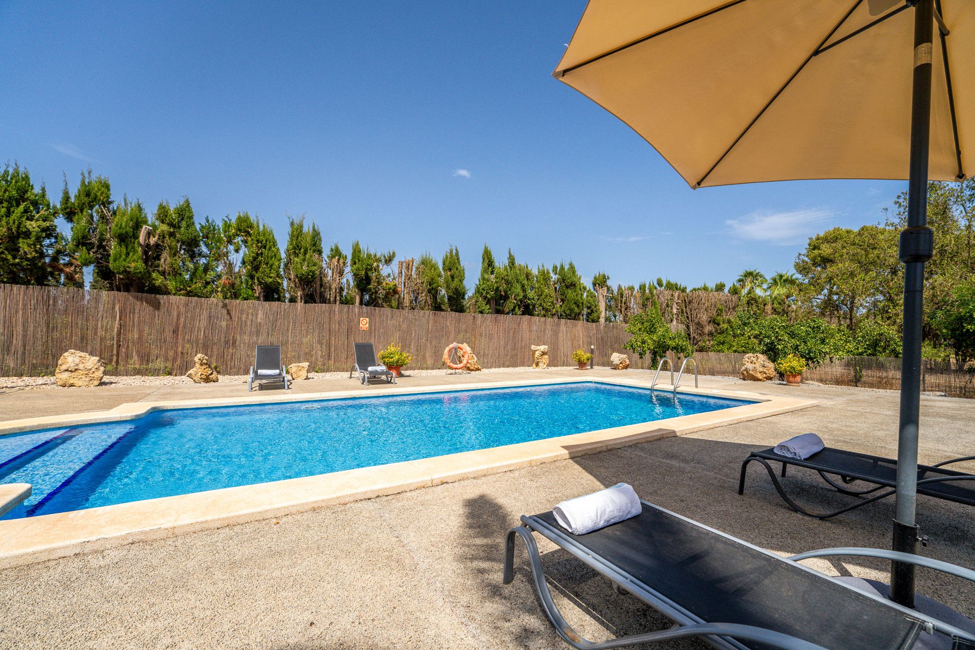 A swimming pool with lounge chairs and an umbrella.