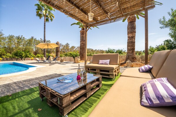 A poolside area with a wooden coffee table, lounge chairs, and a sofa. - Finca with pool Son Manyo 2 Petit in Sa Pobla (Sa Pobla)